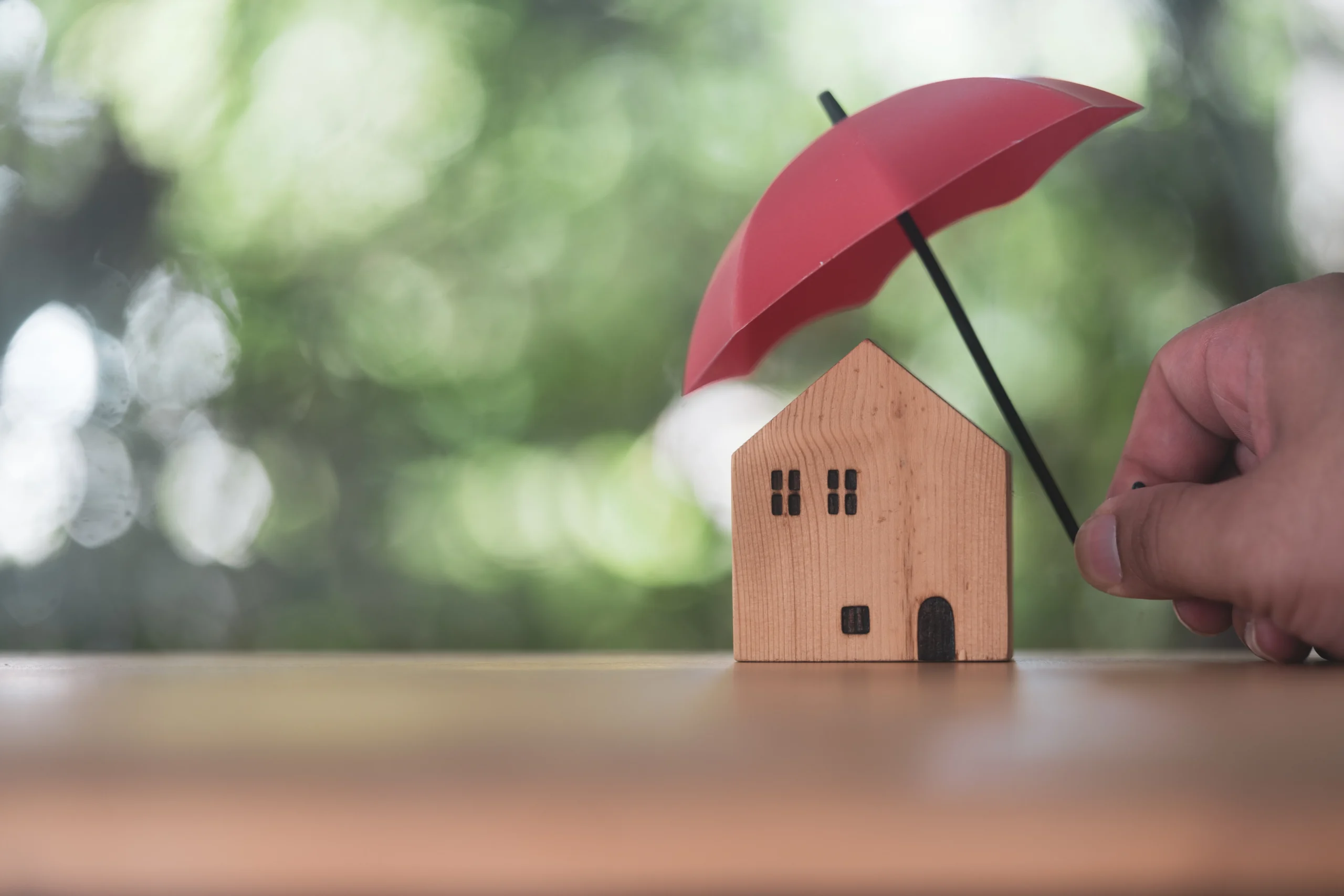 Individuals holding small red umbrellas and model homes, housing insurance against impending loss and fire, building fire insurance, home and real estate insurance concepts.